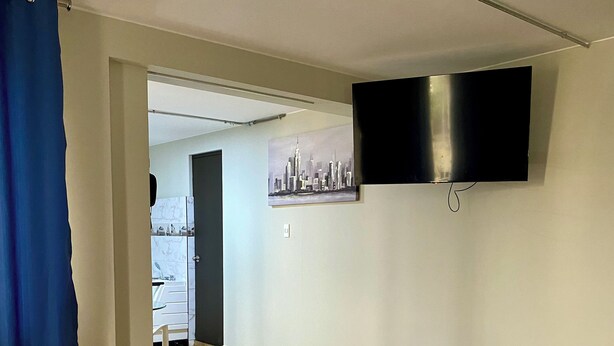 Una habitación de hotel con una cama, un banco, un cuadro y un televisor.