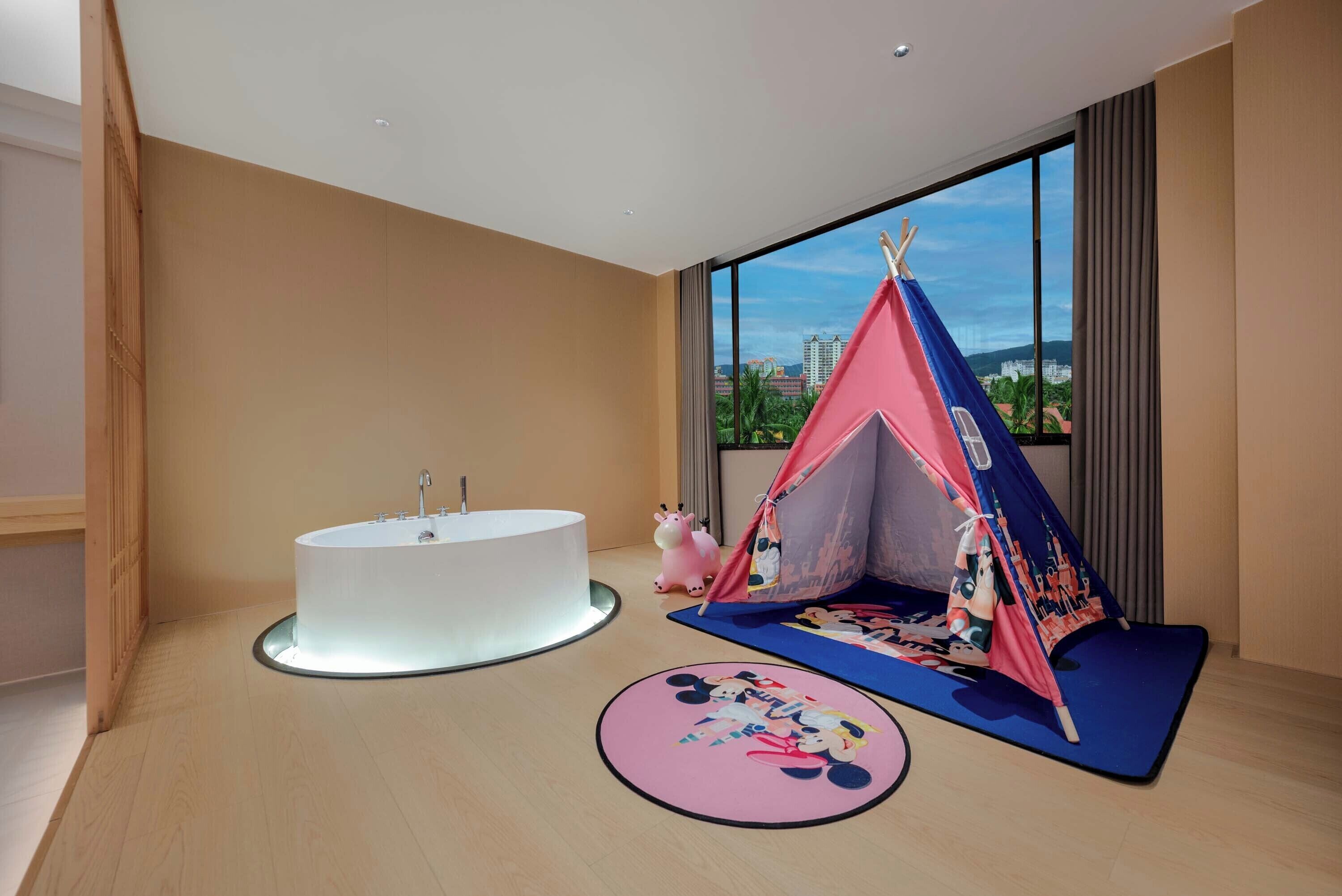 A modern room with a round bathtub, a children's play tent, and a Mickey Mouse-themed rug.