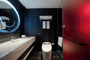 Um banheiro moderno com pia branca, vaso sanitário e parede vermelha. Há um porta-toalhas com duas toalhas e uma placa com caracteres chineses.