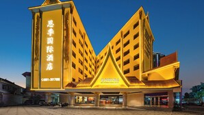 Un hotel con un letrero llamativo en caracteres chinos, diseño arquitectónico moderno y una entrada bien iluminada.