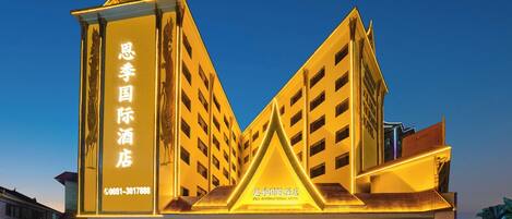 Un hotel con una fachada triangular distintiva y señalización iluminada.
