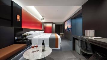 Une chambre d’hôtel moderne équipée d’un lit, d’une table de chevet et d’un coin salon avec une table.