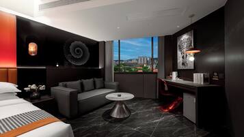 Habitación de hotel moderna con cama, sofá, una mesita y vistas de la ciudad a través de amplios ventanales.