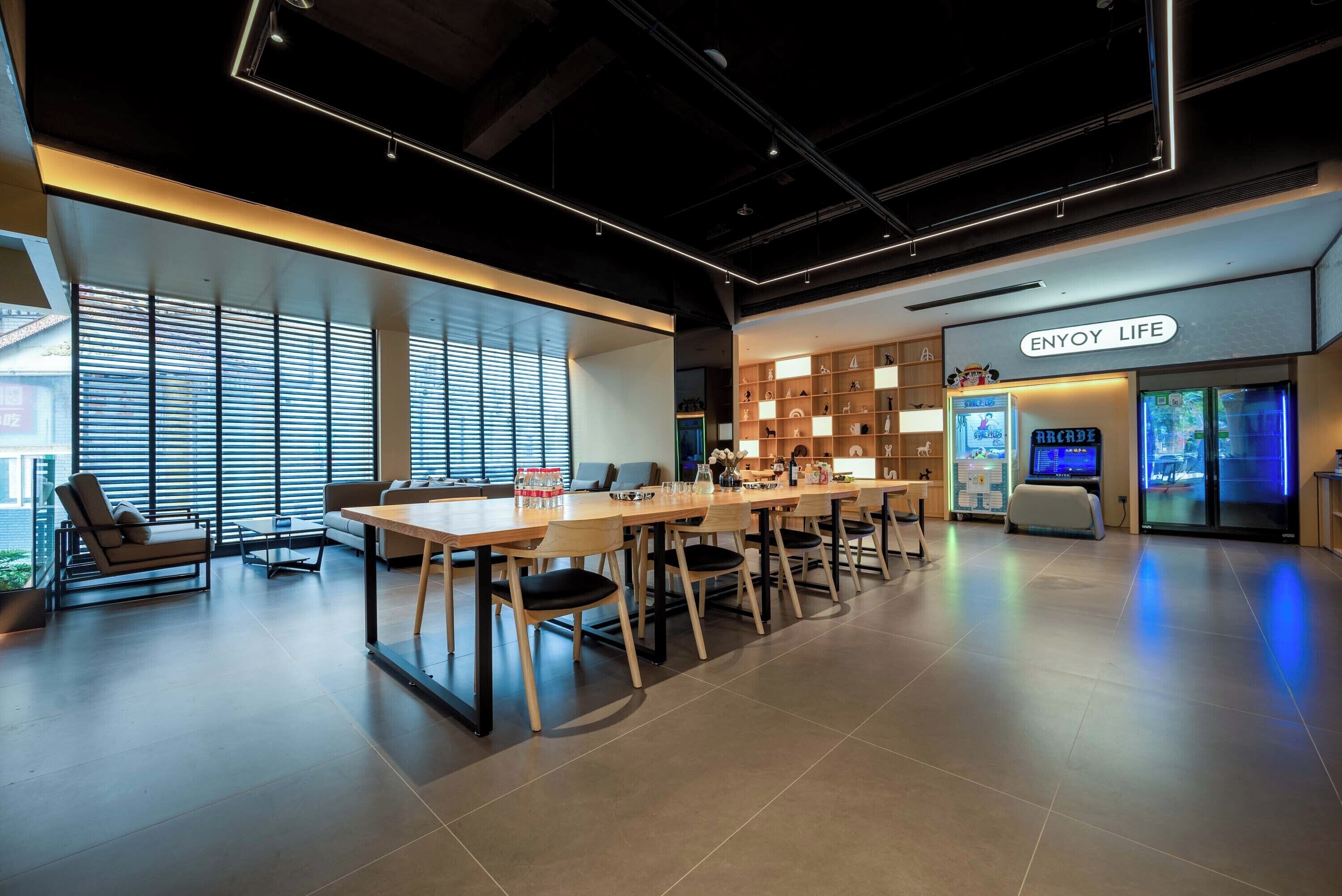 A modern conference room with a long table, chairs, and a large window with blinds.
