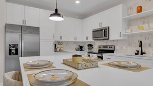 Een moderne keuken met witte kasten, roestvrijstalen apparatuur en een centraal eiland met decoratieve borden.