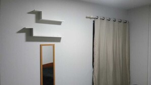 Una stanza con uno specchio, una tenda e una mensola a parete.