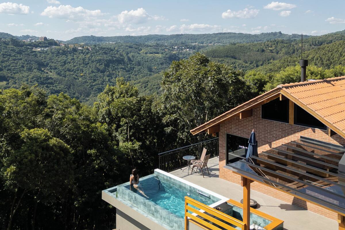 Una casa moderna con piscina en la azotea y vistas a un valle boscoso.