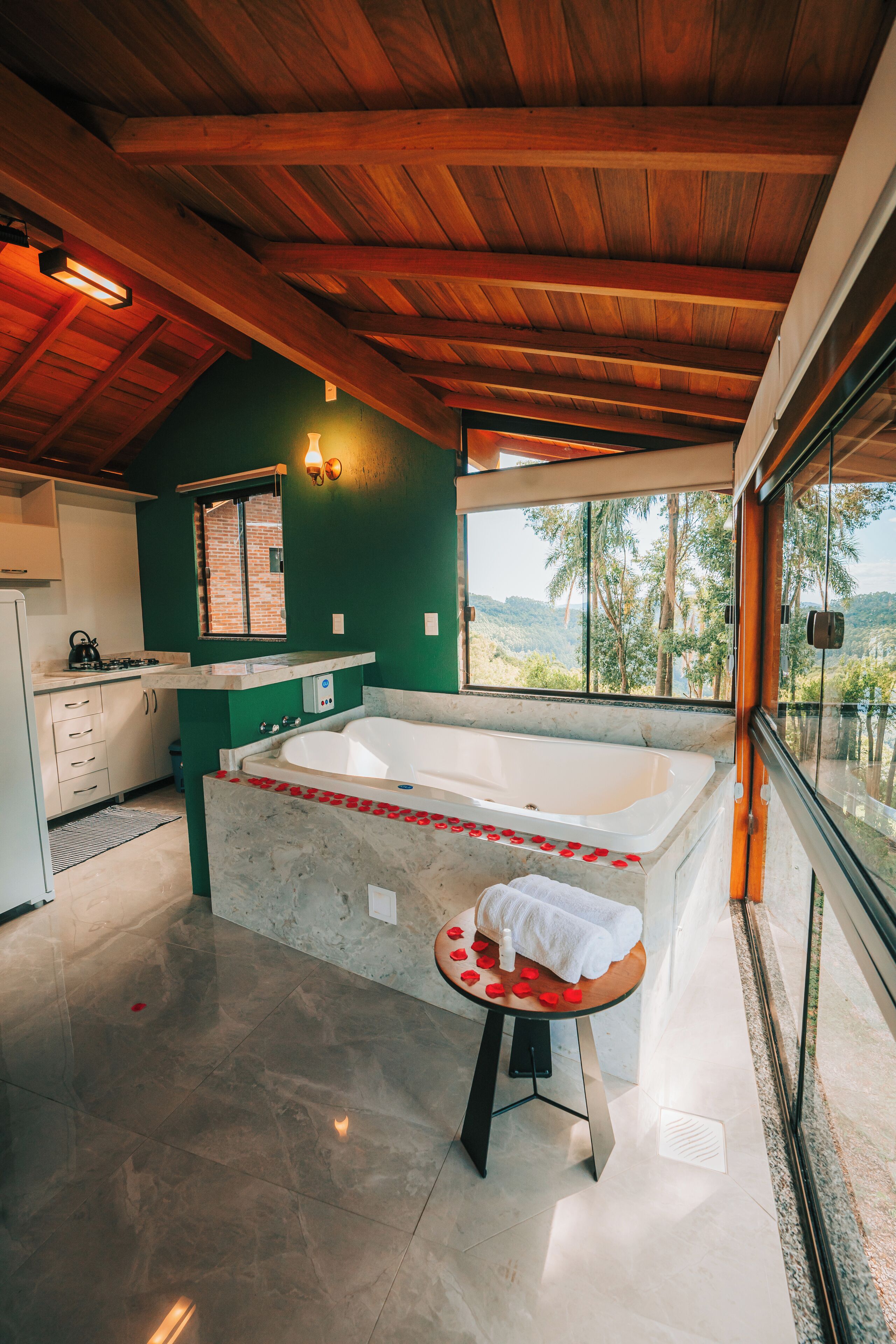 Une salle de bain moderne avec une grande baignoire, une petite table sur laquelle est posée une serviette, et une vue sur l’extérieur.