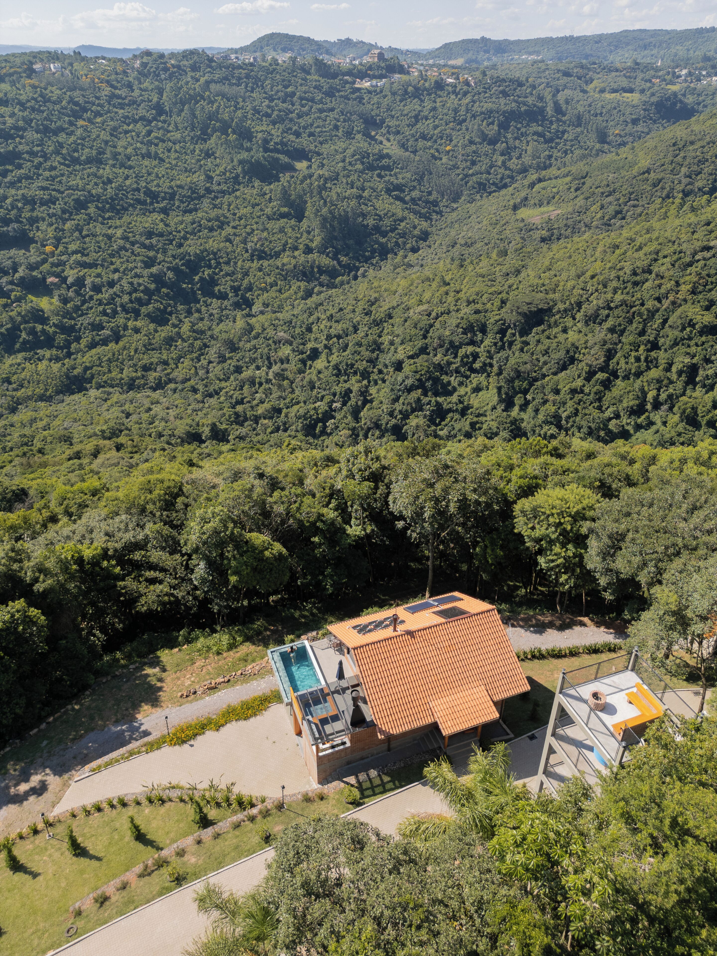 Una villa con piscina, rodeada de un bosque denso y colinas.