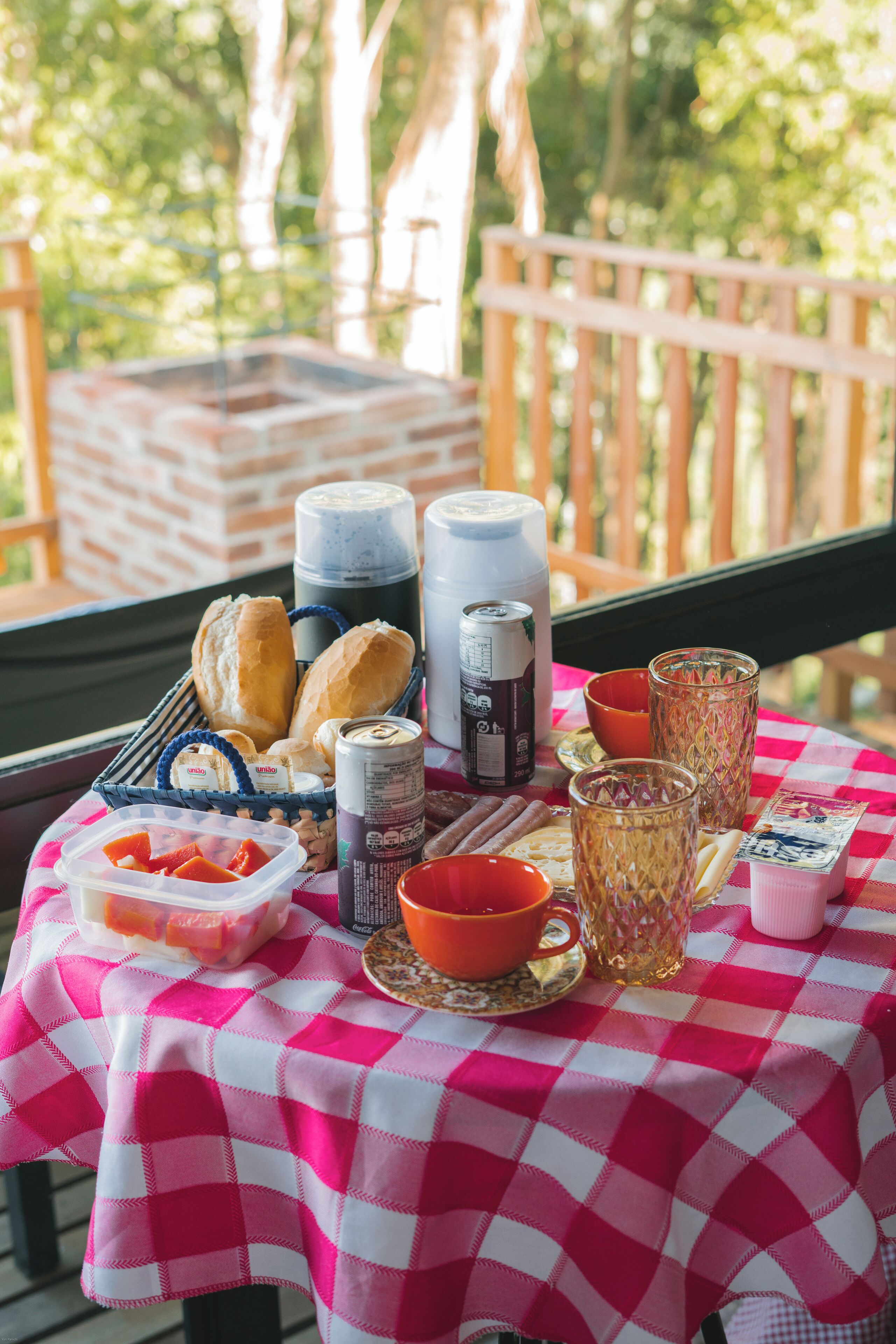 Una mesa con mantel a cuadros, diversos alimentos, bebidas y una cesta de pan.