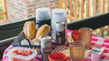 Una mesa con mantel a cuadros, diversos alimentos, bebidas y una cesta de pan.