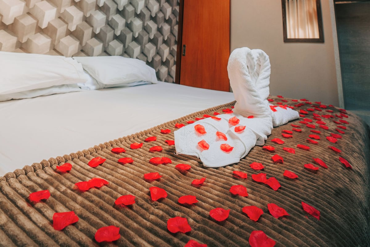 Una habitación de hotel con techo de madera, tragaluz, cama con cabecera texturizada y una toalla sobre la cama.