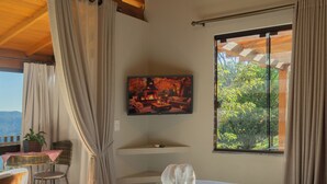 Een hotelkamer met een bed, een stoel, een tafel, een schilderij en een raam met gordijnen.