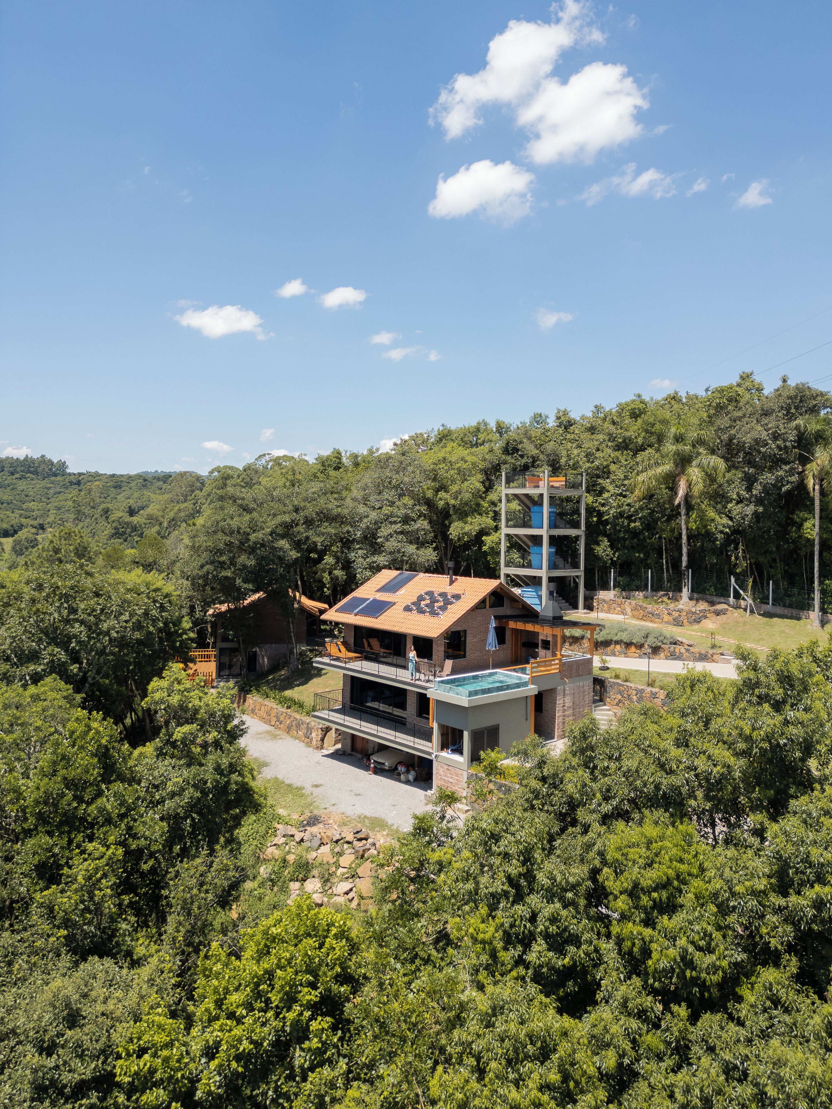 Una casa moderna de dos pisos con techo plano, paneles solares y una piscina.