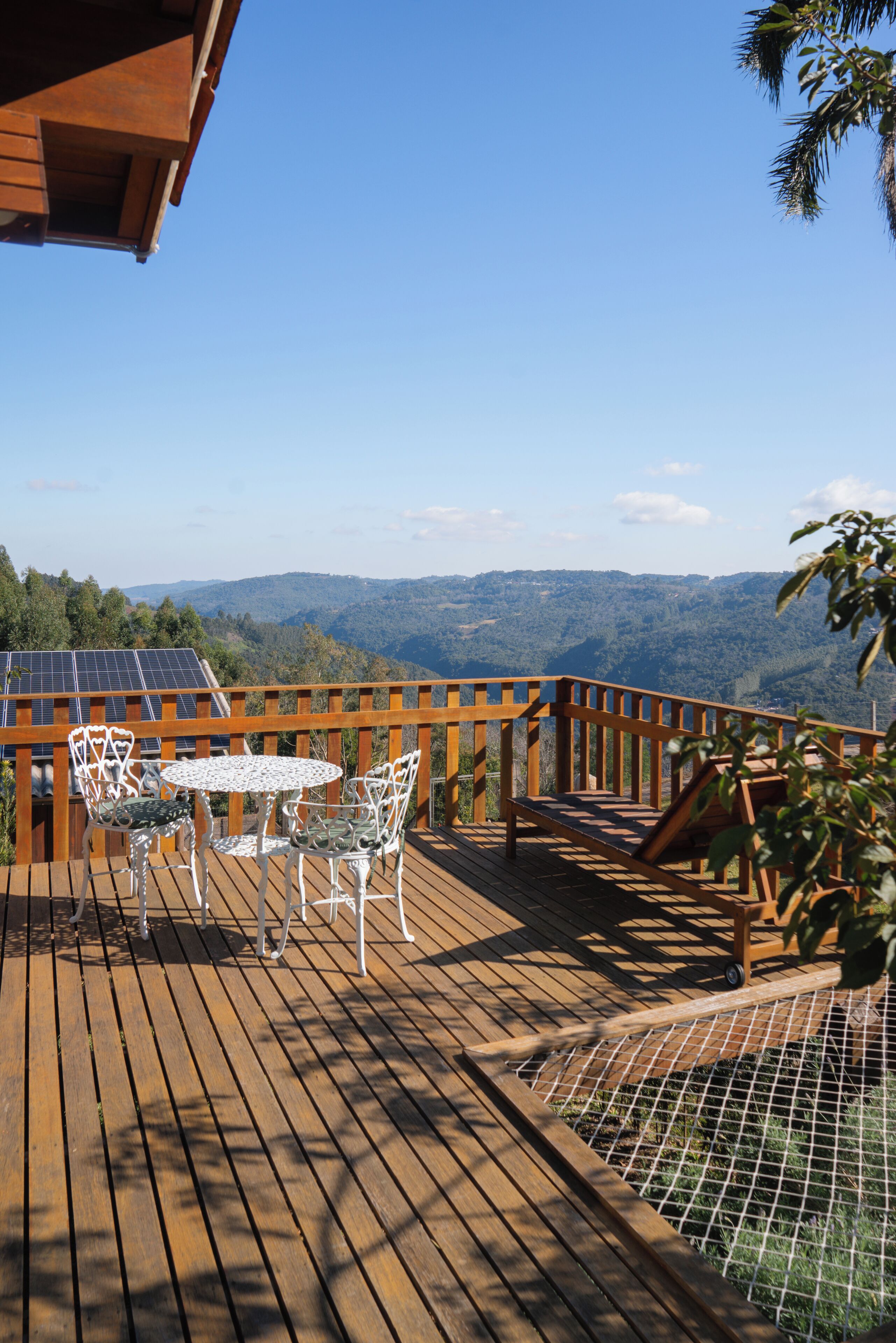 Una terraza de madera con una mesa y sillas, un pequeño rincón de descanso y vistas a las montañas.