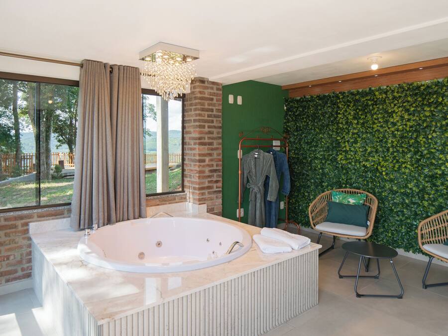 Un baño moderno con una bañera grande, una pared verde, sillas de mimbre y vistas al exterior.
