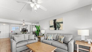 Un salon moderne avec deux canapés gris, une table basse en bois et un ventilateur de plafond.