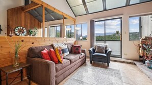 A cozy living room with a brown sofa, a black armchair, and a wooden ceiling. - Beaver Run 28220: Ski-In/Out Peak 9 Condo, Fireplace, Pools & Hot Tubs. (Breckenridge)