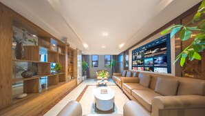 Een moderne woonkamer met een bank, salontafel en houten wandplanken met decoratieve objecten.