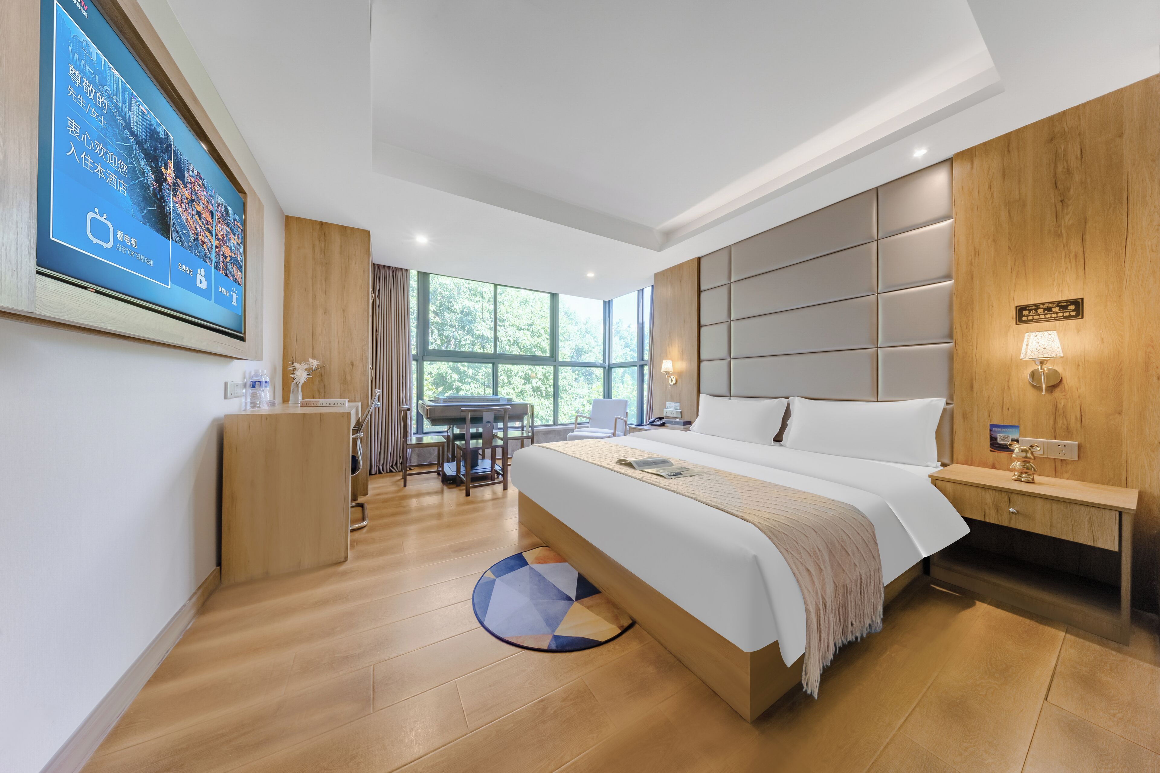 Een moderne hotelkamer met een groot bed, een bureau en uitzicht op groen.