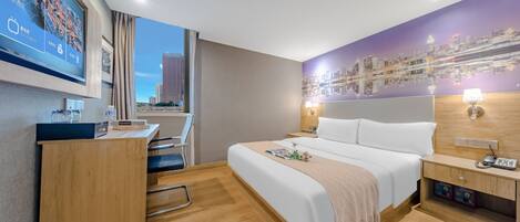 Habitación de hotel con cama, escritorio, silla y televisor que muestra un paisaje urbano.