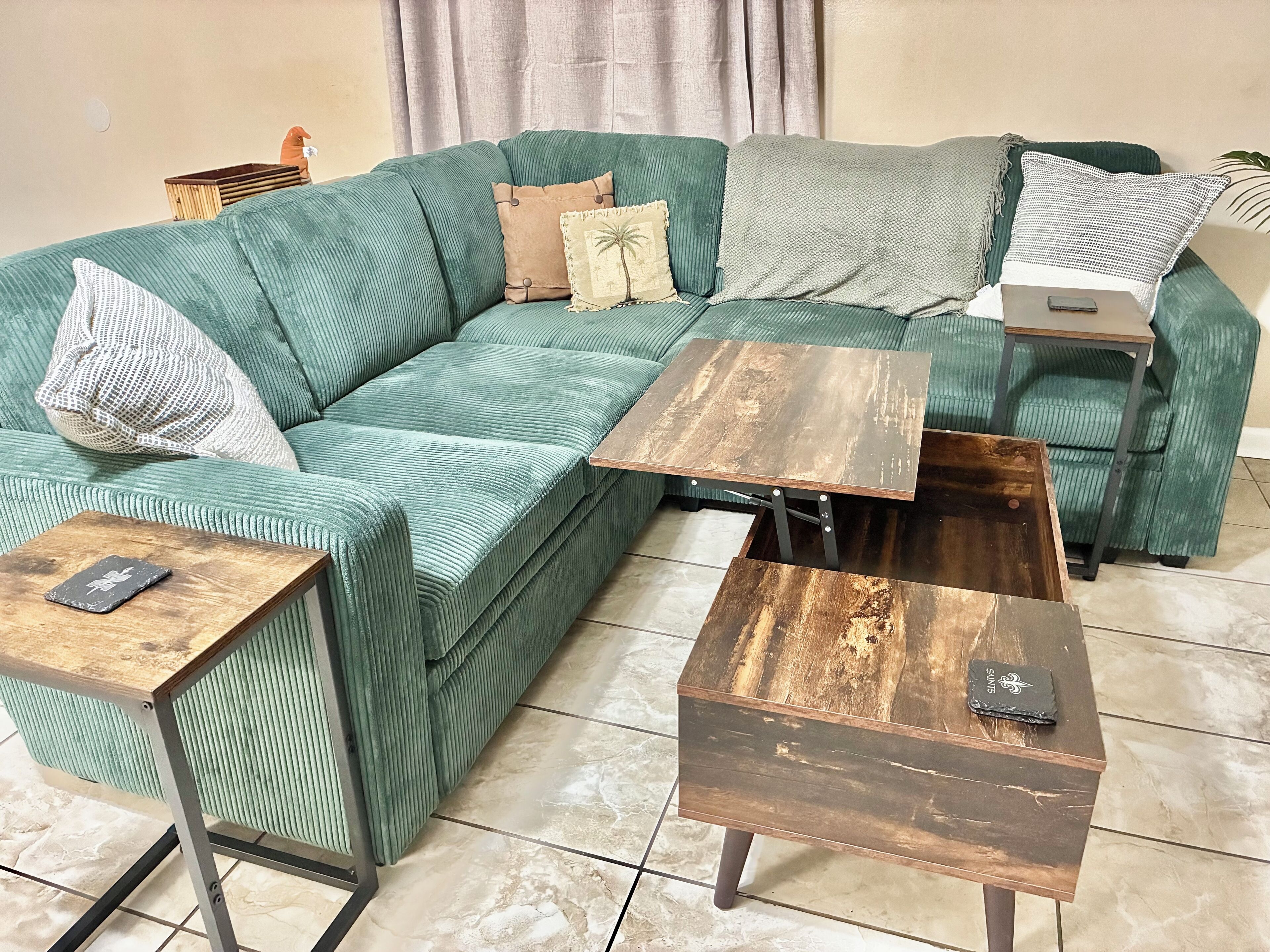 A green sofa with a wooden coffee table and a matching side table.