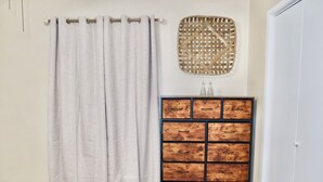 A bathroom with a beige wall, a wooden cabinet with drawers, and a curtain.