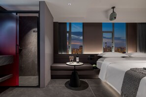 A modern hotel room with a city view, a sofa, a small table with glasses and a bottle, and a bed with a blanket. - ENJI S Shancheng Designer Hotel (Chongqing)