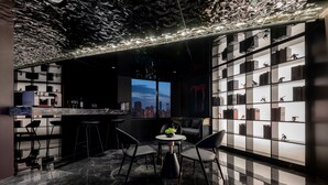 Eine moderne Bar mit Stadtblick, Marmorböden und einer Bücherwand mit Figuren.