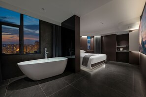 A modern hotel room with a large bathtub, a bed, a city view, and a bathroom with a sink and mirror. - ENJI S Shancheng Designer Hotel (Chongqing)