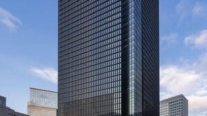 Ein Hochhaus mit einer rasterartigen Fassade, wahrscheinlich ein Geschäfts- oder Bürogebäude.