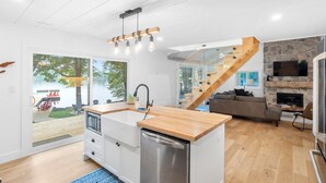 A modern kitchen with a wooden countertop, a built-in dishwasher, and a large window. - Cedar Sauna, Cedar Hot Tub, Lakeside Fire Pit, Private Beach | La Dolce Muskoka (Bracebridge)