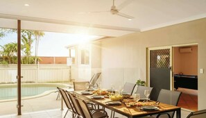 A dining area with a pool view, a ceiling fan, and a sliding door leading to a pool.