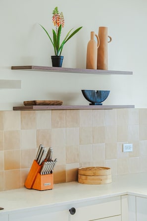 Una cocina con encimera de madera, un bloque de cuchillos, una vaporera de bambú y una planta en maceta.