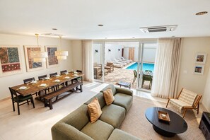 A spacious living area with a dining table set for six, a sofa, and a poolside seating area. - Luxury 4BR Villa | Private Pool | Steps to Beach - Costa Catalina 2 by Bocobay (Noord)
