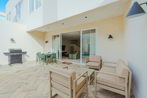 A patio with outdoor furniture, a grill, and a sliding glass door leading to an interior space.
