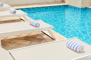 A swimming pool with lounge chairs and towels. - Luxury 4BR Villa | Private Pool | Steps to Beach - Costa Catalina 2 by Bocobay (Noord)