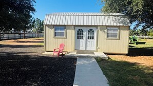 A small, single-story building with a metal roof, a front door, and a small porch area.