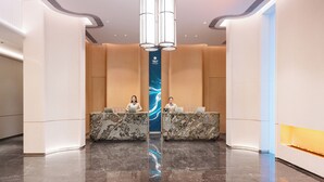 A modern reception area with marble counters, a central blue banner, and a polished marble floor.