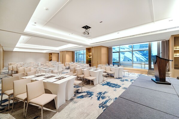 A spacious conference room with multiple tables and chairs, large windows offering a view of the city, and a modern ceiling design. - Beijing XuanLi Hotel (Beijing)