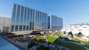 A modern building with reflective glass windows and a unique white structure with a geometric design.