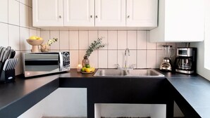 Eine moderne Küche mit weißen Schränken, einer schwarzen Arbeitsplatte, einer eingebauten Spüle, einer Kaffeemaschine und einer Mikrowelle.