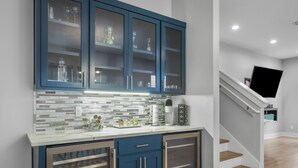 Een moderne keuken met blauwe kastjes, een betegelde spatwand en een koffiezetapparaat op het aanrecht.
