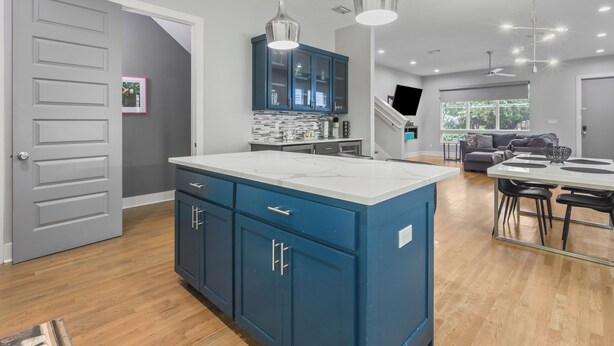 Een moderne keuken met blauwe kastjes, een wit aanrecht en hangende lampen.