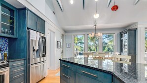 A modern kitchen with dark blue cabinets, stainless steel appliances, and a large island with a marble countertop. - Golf Course view secluded home in the heart of BHI (Bald Head Island)
