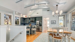 A spacious kitchen with a central island, dark cabinets, and a blue tiled backsplash. - Golf Course view secluded home in the heart of BHI (Bald Head Island)