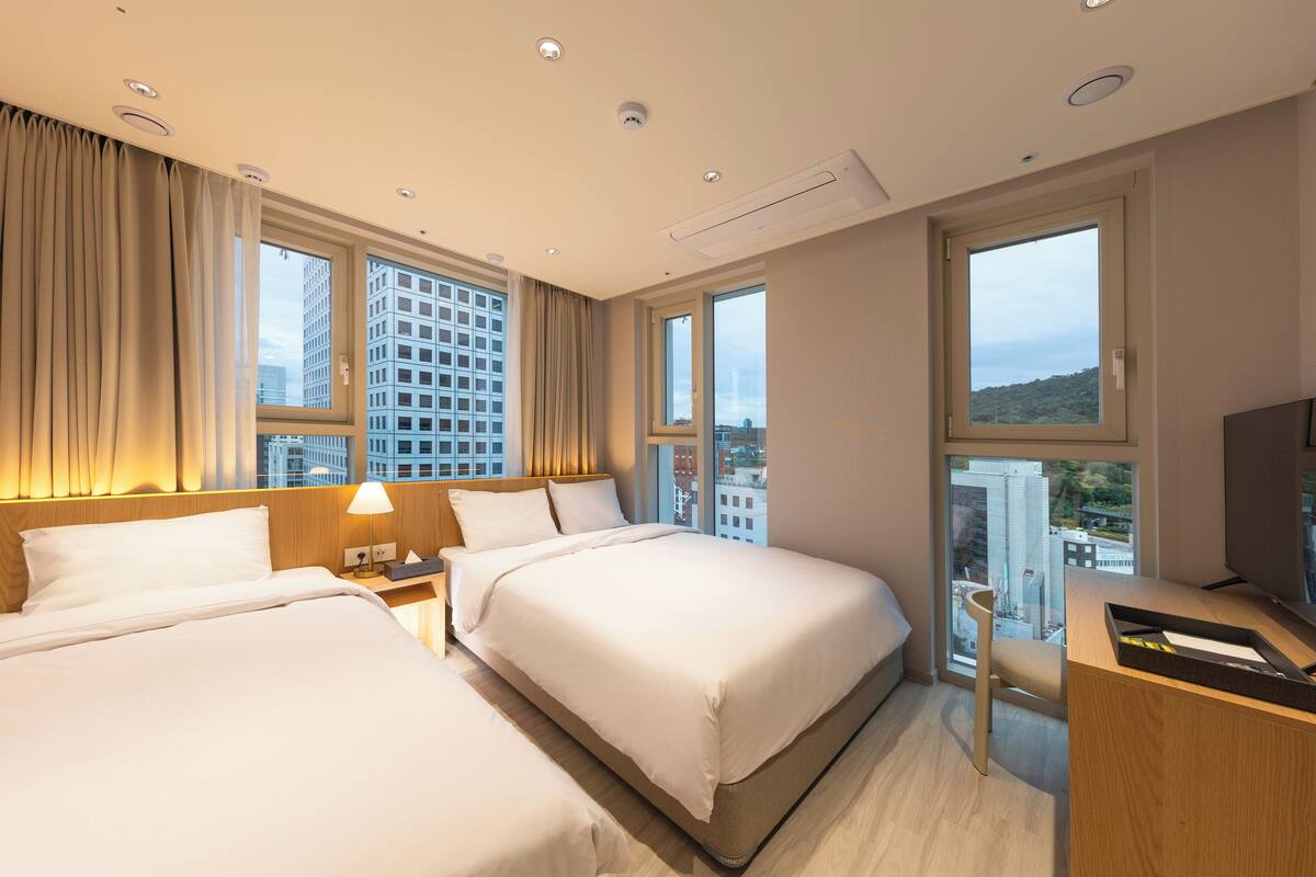 A hotel room with two beds, a desk, and a TV.