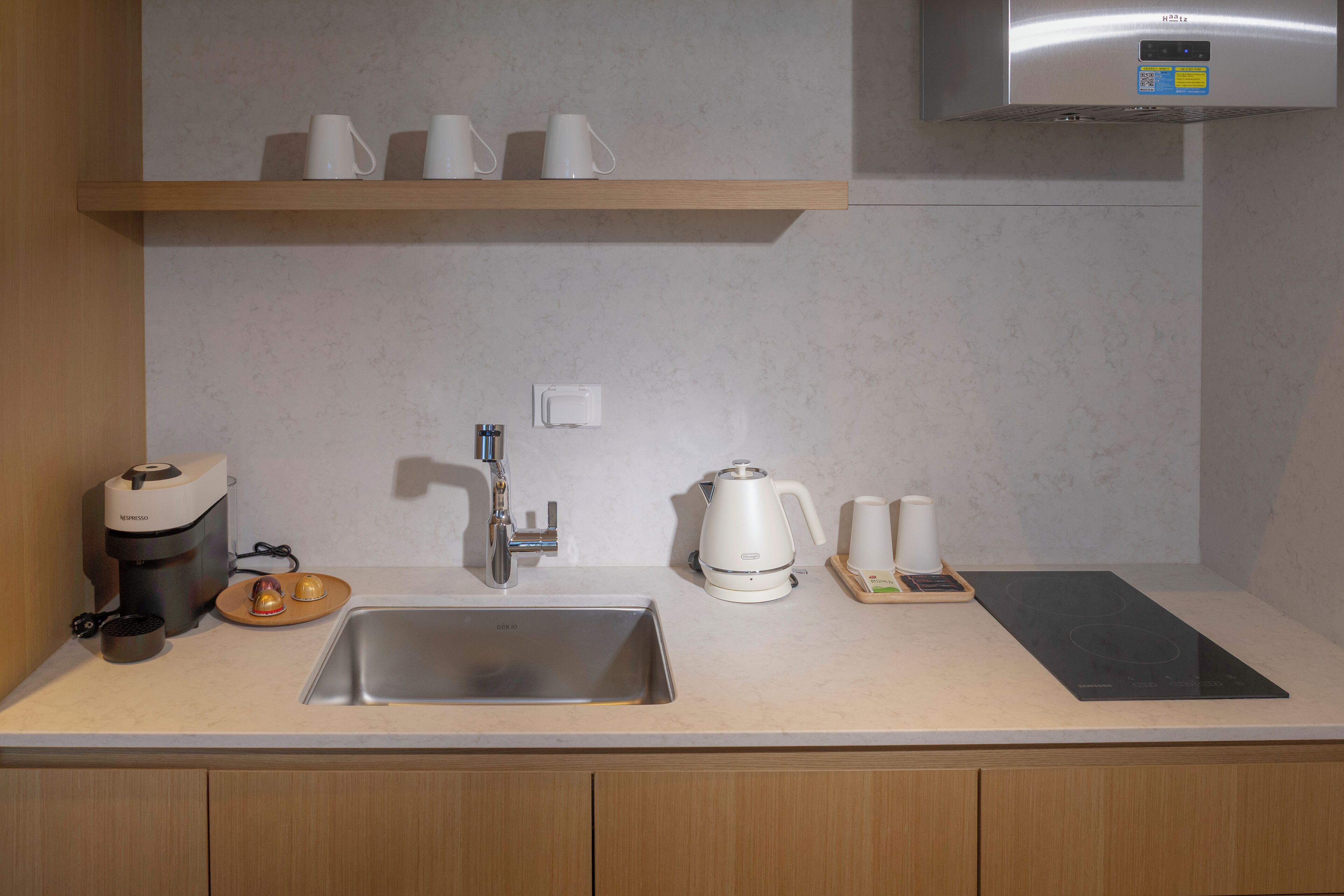 A modern kitchen with a stainless steel sink, a coffee maker, a kettle, and a toaster.