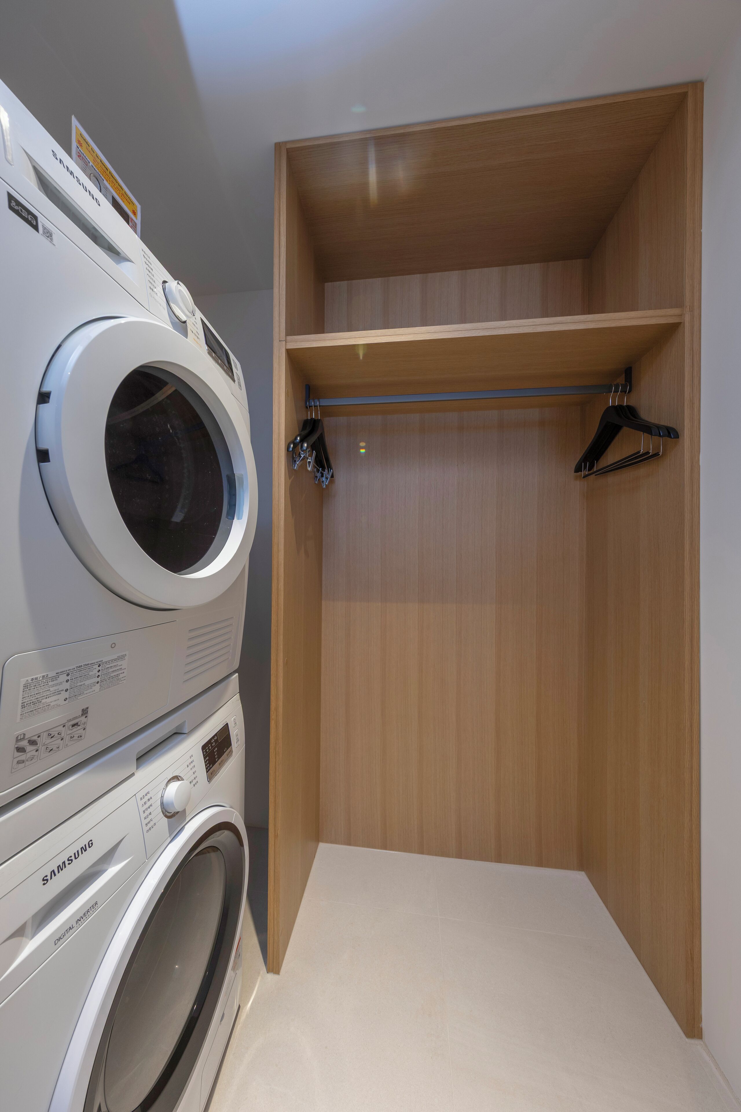 Un espace buanderie équipé d’un lave-linge et d’un sèche-linge Samsung, d’étagères en bois et d’un porte-vêtements en métal.