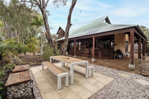 Ein Holzhaus mit überdachter Veranda, einer Steinsitzbank und einem kleinen Tisch.